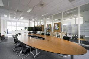 Vergaderruimte met ovale houten tafel, stoelen, digitale schermen en BCC-verlichting aan de Van der Madeweg.